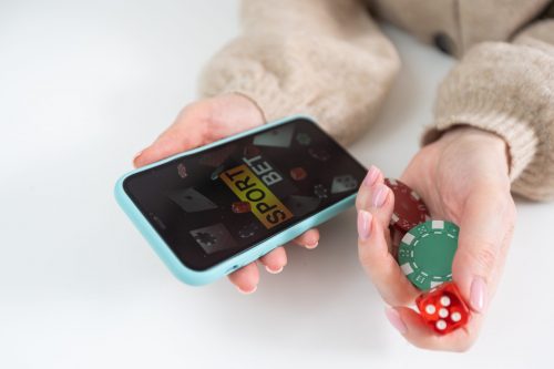 Person holding a smartphone displaying a sports betting interface with casino chips, representing the online gaming market in Mexico.